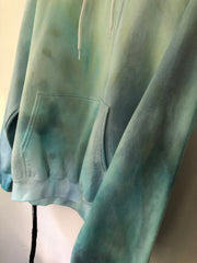 close up of a organic fabric dyed hoodie with blue and green coloring